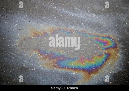 Mehrfarbige Ölpest auf Asphaltstraße, Hintergrund Stockfoto