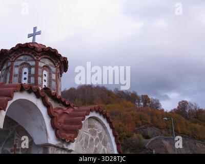 Kleine orthodoxe Bergkirche mit Kreuz in Rodopi, Ostgriechenland. Malerische Aussicht und bewölkter Himmel. Stockfoto