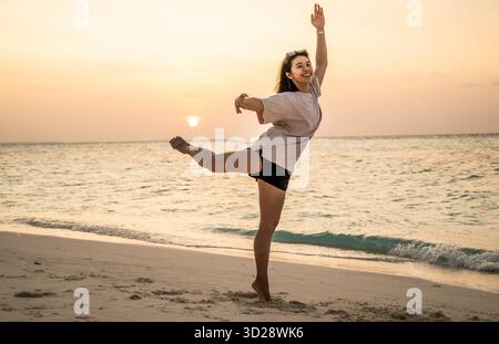 Schöne Frau, die sich als Ballerina am Strand auf den Malediven ausgibt Stockfoto