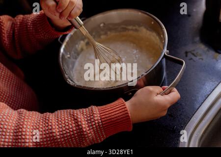 Kind, das Teig in einer Metallschüssel auf der Küchenzeile rührt Stockfoto