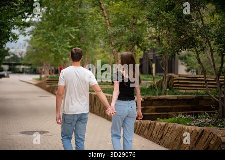 Junge gesichtslose Paare halten liebevoll Hände im City Park Stockfoto