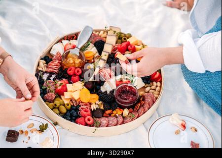 Die Gruppe genießt eine Wurstplatte mit verschiedenen Aufschnitt- und Käsesorten Stockfoto