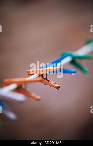 Regentropfen hängen an bunten Kleiderschalen auf einer Wäscheleine Stockfoto