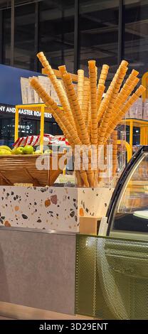 Doloman, Türkei - 25. April 2025: Eiskegel stehen neben frischen Äpfeln in einem modernen Dessertgeschäft. Stockfoto