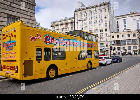 Leuchtend gelber Hop-on-Hop-off-Sightseeing-Bus auf der Liverpool Street, historische Gebäude und städtische Architektur im Hintergrund unter dem Frühlingshimmel. Stockfoto