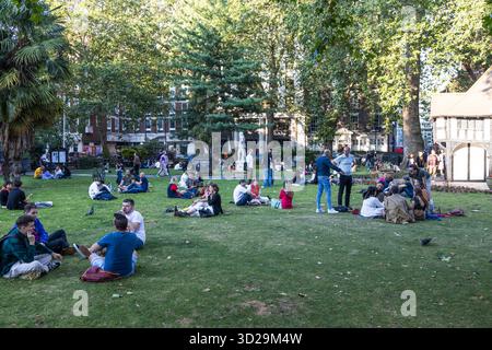 Menschen, die sich auf dem Rasen im Stadtpark entspannen. London, UK, 23. Juli 2023 Stockfoto
