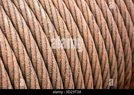 Seilzug aus Stahl. Alte veraltete rostigen Stahl geflochtene Kabel auf Trommel der industriellen Winde Makro Nahaufnahme Textur Hintergrund verwundet. Stockfoto