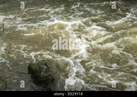 Borken-Hoxfeld, NRW, Deutschland, die Szene zeigt einen schnell fließenden Fluss mit klarem Wasser, das über glatte Felsen plätschert. Blasen bilden sich, wenn das Wasser rast p Stockfoto