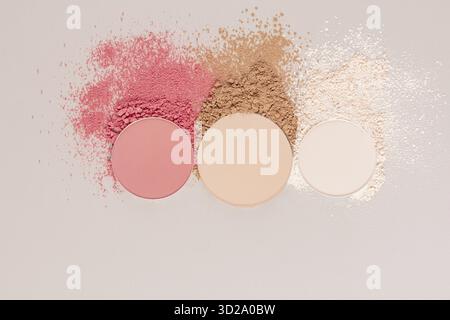 Drei Blöcke des Kosmetikprodukts, trockenes Rouge in rosa Ton, kompaktes Pulver in Beige, heller Ton, Texturproben von losem Pulver. Draufsicht Stockfoto