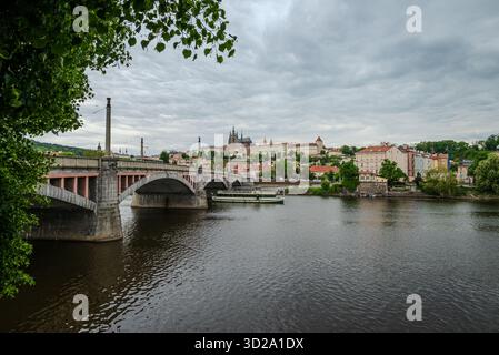 Manes-Brücke über die Moldau in Prag, Tschechien, unter weichen Maiwolken, mit Fernsicht auf die Prager Burg Stockfoto