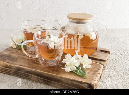 Teezeremonie. jasmintee mit raffiniertem blumigem Aroma in Glasbechern und einem Wasserkocher wird auf einem originalen Holzbrett serviert Stockfoto