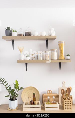 Offene Küche Holzregale mit Gläsern für die Lagerung auf einer weißen strukturierten Wand und ein Teil der Arbeitsplatte mit umweltfreundlichen Gegenständen für die Lagerung Stockfoto