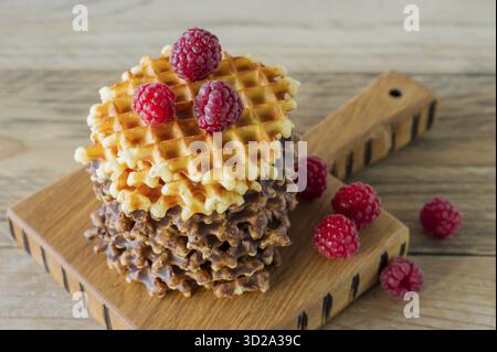 Köstliche belgische Waffeln mit Resbeerbelag auf hölzernem Schneidebrett. Leckeres Frühstück Stockfoto