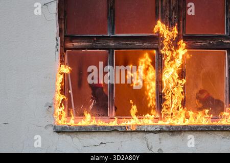 Ein Feuerwehrmann rettet ein Baby aus einem brennenden Gebäude. Der Feuerwehrmann ist in Aktion und rettet das Kind aus der Notsituation. Dieses Bild kann verwendet werden, um Themen von Tapferkeit, Rettungseinsätzen und Rettungsdiensten zu veranschaulichen. Stockfoto