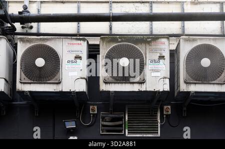 Manchester, großbritannien, 19. Januar 2025 Industrieklimaanlagen, montiert an der Gebäudefassade mit verwittertem Außenbereich und freiliegenden Rohren Stockfoto