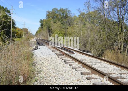 Verrostete Eisenbahnschienen mit zusätzlichen Schienen für Entgleisungsschutz und strukturelle Stabilität, wenn sie entlang einer Brücke über eine örtliche Straße oder Straße fahren. Stockfoto