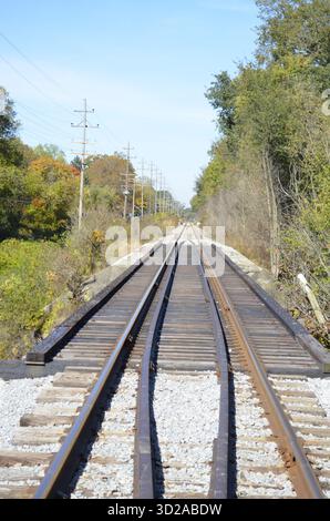 Verrostete Eisenbahnschienen mit zusätzlichen Schienen für Entgleisungsschutz und strukturelle Stabilität, wenn sie entlang einer Brücke über eine örtliche Straße oder Straße fahren. Stockfoto