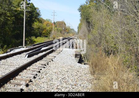 Verrostete Eisenbahnschienen mit zusätzlichen Schienen für Entgleisungsschutz und strukturelle Stabilität, wenn sie entlang einer Brücke über eine örtliche Straße oder Straße fahren. Stockfoto