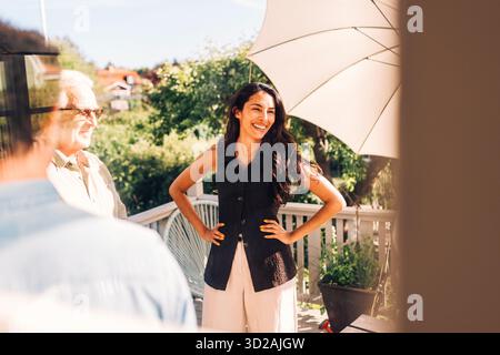 Glückliche Frau mit Armen akimbo, die auf der Veranda der Villa steht Stockfoto