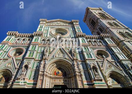 Prunkvolle neogotische Fassade der Kathedrale von Florenz (Dom), Santa Maria del Fiore und Giottos Campanile vor einem hellblauen Himmel. Stockfoto