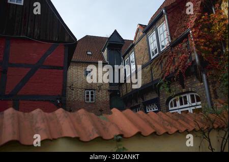 Flensburg, Schleswig-Holstein das Foto zeigt einen historischen Innenhof in Flensburg, Marienstraße mit Blick auf die ehemalige Hökerei J. P. Christiansen. Sichtbar sind mehrere Fachwerkhäuser mit Backsteinfassaden, weiße Sprossenfenstern und rotem Dach, sowie herbstliches Fassadengrün. Im Vordergrund verläuft ein gelber Gartenzaun mit roten Dachziegeln. Aufnahme vom 31.10.2025, Flensburg *** Flensburg, Schleswig Holstein das Foto zeigt einen historischen Innenhof in Flensburg, Marienstraße mit Blick auf die ehemalige Hökerei J P Christiansen sichtbar sind mehrere Fachwerkhäuser mit Backsteinfassade Stockfoto