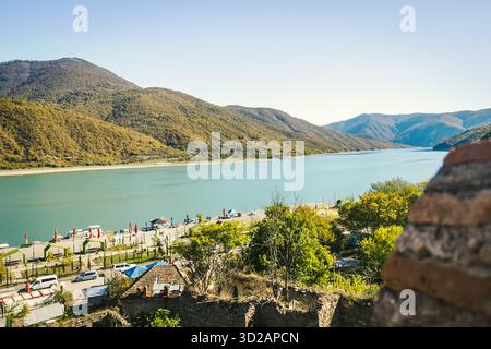 Bergsee mit türkisfarbenem Wasser, umgeben von bewaldeten Hügeln unter einem klaren blauen Himmel. Ruhiger Blick auf die Natur an einem sonnigen Herbsttag im Kaukasus Stockfoto