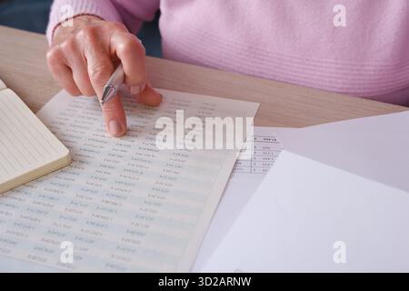 Senior Frau, die zu Hause Finanzdokumente und Berechnungen überprüft Stockfoto