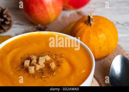 Warme Schüssel cremige Kürbissuppe mit knusprigen Croutons und Kräutern. Perfekt für Herbstrezepte, gemütliche Food Blogs und saisonale kulinarische Themen Stockfoto