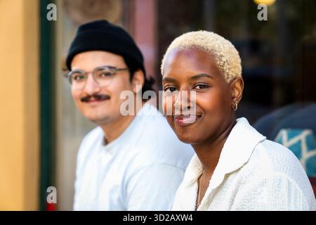 Porträt einer lächelnden Besitzerin mit einer Verkäuferin im Hintergrund Stockfoto