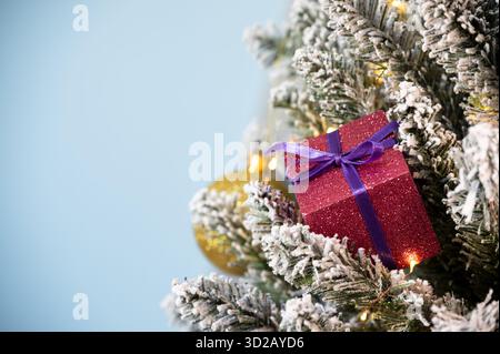 Weihnachtsbaumschmuck auf verschneite Kiefer auf blauem Hintergrund. Stockfoto