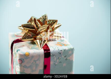 Weihnachtsgeschenk mit Dekoration und goldener Schleife auf blauem Hintergrund. Stockfoto