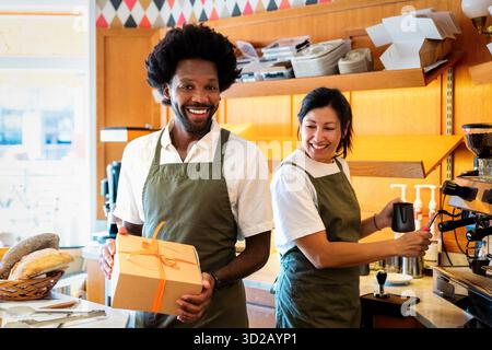 Lächelnde Baristas, männlich und weiblich, arbeiten im Café zusammen Stockfoto