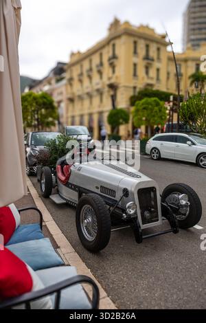 2025.Ein einzigartiger silberner Oldtimer mit einem hellroten Lederinnenraum parkt in einer Monte Carlo Straße neben modernen Autos. Stockfoto