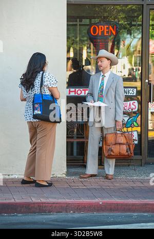Mann mit Anzug, stetson und Cowboystiefeln, die mit einer Frau auf der Straße in Downtown Tucson, Arizona reden Stockfoto