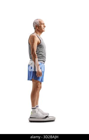Profilaufnahme in voller Länge eines fitten reifen Mannes in Sportbekleidung, der auf einer Waage steht, isoliert auf weißem Hintergrund Stockfoto