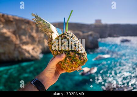 Ananascocktail in der Hand von Blue Lagoon Waters auf Comino, Malta Stockfoto