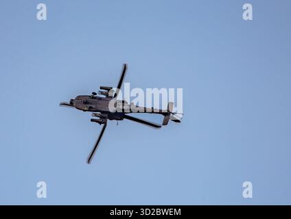 Militärischer Angriff Apache Helikopter, der in einem Winkel gegen einen klaren blauen Himmel während eines Flugmanövers in Salisbury Plain Wiltshire UK fliegt Stockfoto