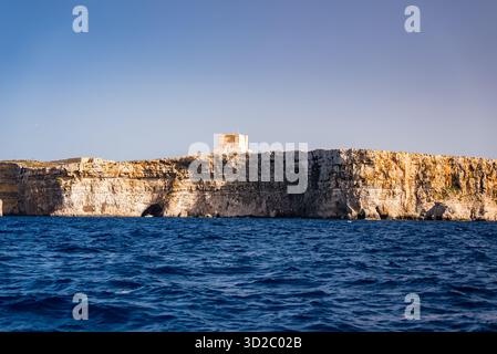 Santa Marija Tower auf Comino über kobaltblauem Wasser zur goldenen Stunde Stockfoto