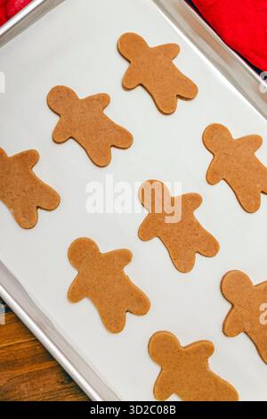 Frisch geschnittene Lebkuchenkekse werden auf einem Backblech angeordnet, fertig zum Backen. Stockfoto