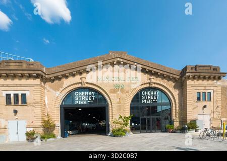 Ein großes Gebäude mit einem grünen Schild auf dem Cherry Street Pier steht. Das Gebäude ist alt und hat viele Fenster Stockfoto