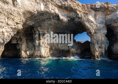 Comino Island Meeresbogen und Höhlen mit Wellen in hellem Sommerlicht Stockfoto