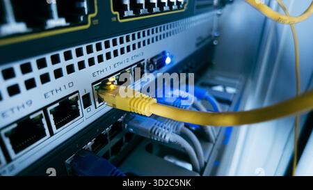 Netzwerk-Switch mit gelbem ethernet-Kabel, das an den Port angeschlossen ist, zeigt moderne Dateninfrastruktur, Hochgeschwindigkeitsverbindung und IT-Systeme Stockfoto