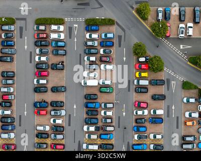 Autos in verschiedenen Farben parkten ordentlich in Reihen auf einem großen öffentlichen Parkplatz. Stockfoto