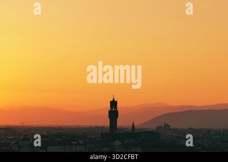 Goldener Sonnenuntergang über der Skyline der Stadt mit historischen Turmsilhouetten und Berghorizont Stockfoto