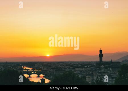 Goldener Sonnenuntergang über der Skyline der Stadt mit historischen Turmsilhouetten und Berghorizont Stockfoto