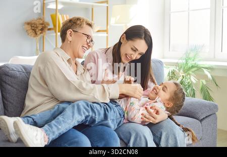 Glückliche Familie, Großmutter, Mutter, Kind, sitzend auf Sofa im modernen Wohnzimmer, drei Generationen Stockfoto