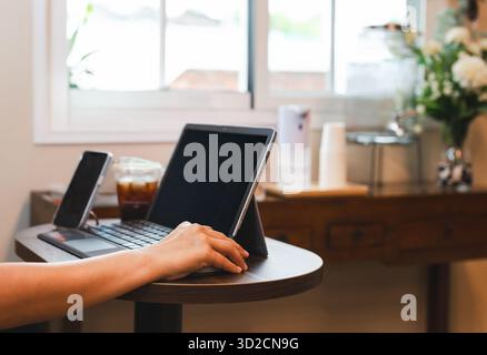 Konzentrieren Sie sich auf die Hand mit der Maus Geschäftsfrau, die im Café mit dem Handy auf dem Tisch arbeitet. Stockfoto