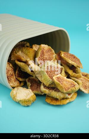 Getrocknete Feigenscheiben, die aus einem weißen Behälter verschüttet werden Stockfoto