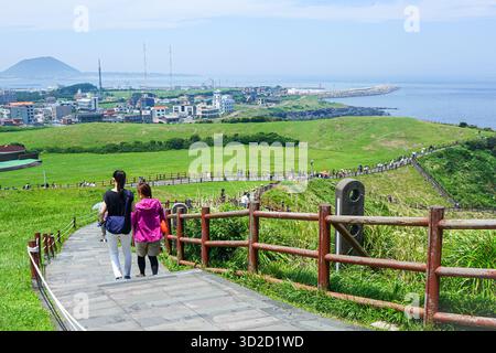 Touristen auf dem Fußweg über dem Seongsan-ri Haenyeo Woman Diver Village an der Umutgae Coast im Seongsan Ilchubong Park, auch Sunrise Peak genannt Stockfoto