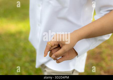 Selektiver Diamant-Ring aus Gold an der Hand der jungen Frau Er hält die Hand einer jungen Frau, nachdem er einen Ring aufgelegt und ihr einen Antrag gemacht hat. Stockfoto
